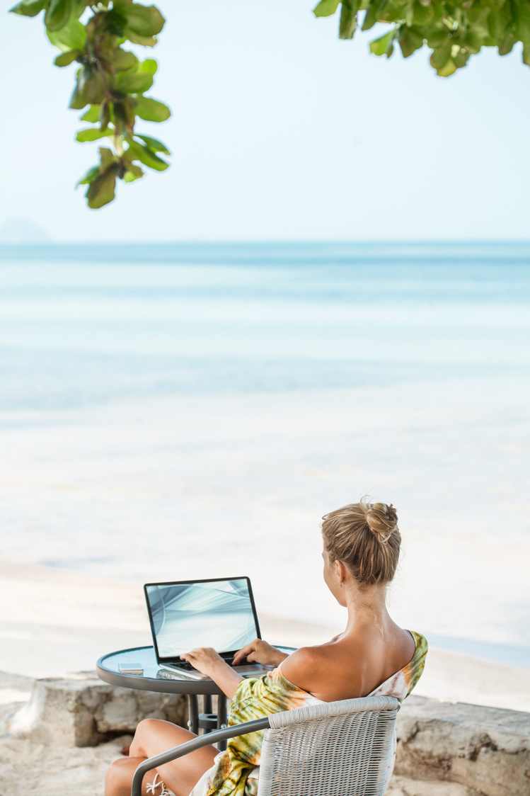 Woman at beach working on laptop